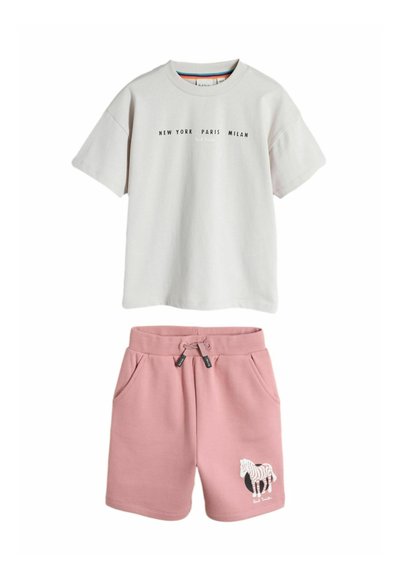 Hvid T-shirt med korte ærmer med teksten "New York Paris Milan" og pink shorts med snøre samt et zebragrafik på venstre ben.