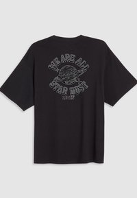 T-shirt en coton noir à manches courtes avec un graphisme blanc représentant une planète et le texte "NOUS SOMMES TOUS DE LA POUSSIÈRE D'ÉTOILES" au-dessus.