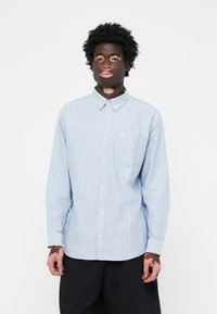 Lichtblauw overhemd met lange mouwen en witte verticale strepen, met een button-down kraag en één borstzak. Gemaakt van een gladde stof.