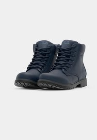 Bottes synthétiques bleu marine avec un design à cheville haute, dotées de lacets noirs, d'une semelle robuste et de détails de logo subtils sur la languette.