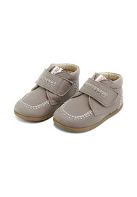 Botines de cuero gris con pespuntes blancos y una correa de Velcro. Forro interno suave y suelas de goma para mayor agarre. Diseño bajo.