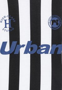 Black and white striped fabric t-shirt featuring a blue graphic text "Urban" and logos for "High-Class Studio" and "International."