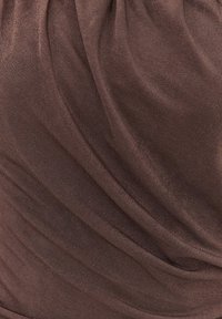 Tissu brun avec des plis doux et une surface lisse, légèrement texturée, créant des ombres douces.