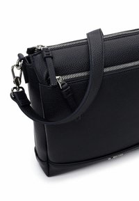 Czarna skórzana torebka z teksturowaną powierzchnią, wyposażona w podwójne srebrne zamki błyskawiczne i odpinany pasek na ramię.
