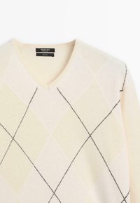 Pull à col en V en 100 % laine, avec une base beige clair et un motif en losange jaune pâle agrémenté de surpiqûres noires.