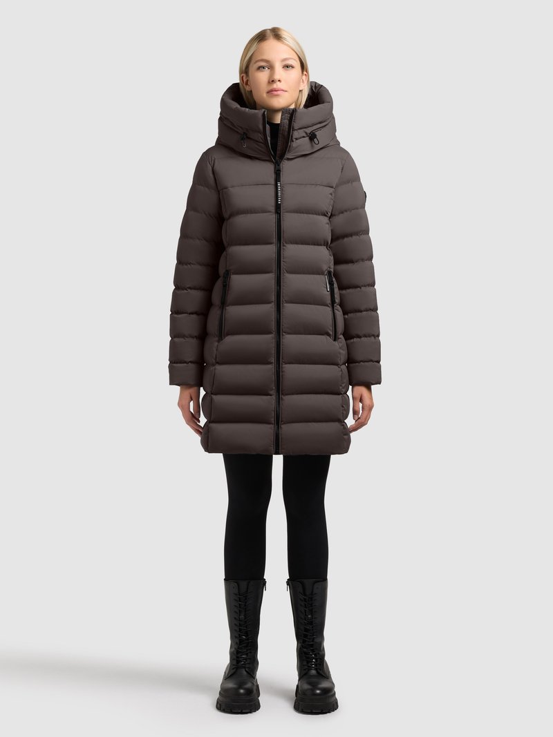 Kurtka puchowa w ciemnoszarym kolorze, z wysokim kołnierzem, bocznymi kieszeniami na zamek oraz lekko taliowanym krojem. Do kompletu czarne legginsy i botki na sznurowadła.