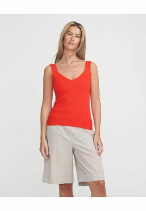 Rød ribbet tanktop med v-snit, parret med beige og hvide stribede shorts, der har en afslappet pasform og opfoldede kanter.