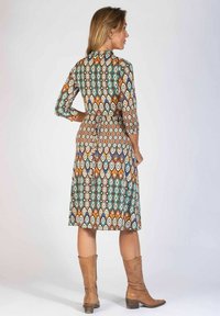 Gestreiftes Kleid mit Dreiviertelärmeln, das ein geometrisches Design in Türkis, Orange und Braun aufweist. Knielang mit einem taillierten Gürtel.