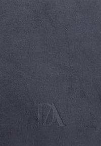 Tejido de ante de cuero en color navy que presenta un logo sutilmente grabado. La textura parece suave y mate, sin patrones ni acentos visibles.