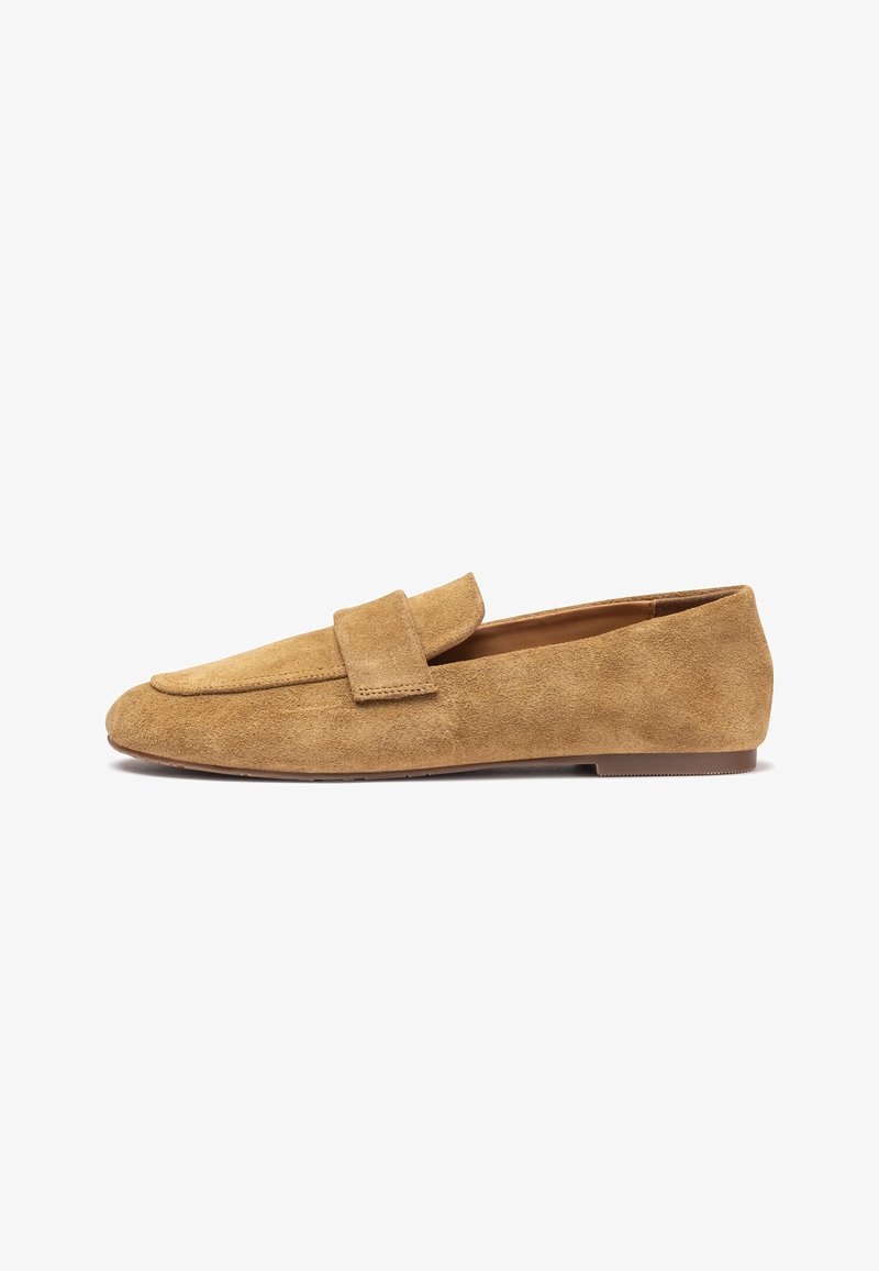 Mocassins en daim beige avec un bout arrondi, une couture, et un détail replié sur le devant ; semelle plate, design minimaliste.