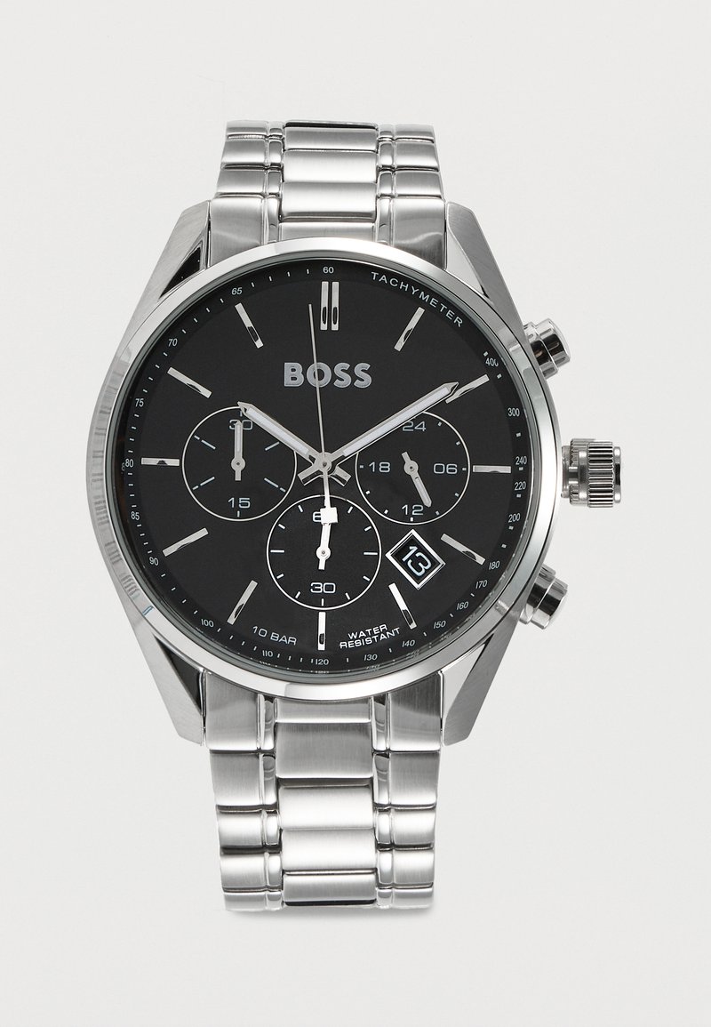 Montre-bracelet en métal argenté avec cadran noir, trois sous-cadrans, affichage de la date à 4 heures et échelle tachymétrique autour du bord.