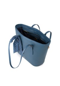 Borsa a tracolla in pelle blu con sciarpa decorativa staccabile sul manico, tasca con zip interna aperta e lunghe spalline su sfondo bianco.