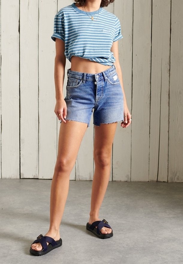 Modrý a bílý pruhovaný krátký rukáv crop top spárovaný s denimovými šortkami s třepenými okraji. Tmavé sandály s tlustou podrážkou dokončují celkový vzhled.