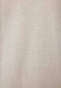 Light beige cotton fabric with a fine, textured surface, showing a subtle, uniform pattern. Suitable for versatile clothing applications.