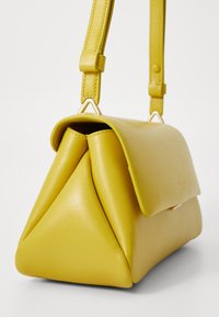 Yellow leather handbag with a triangular design, a flap closure, and an adjustable strap. Features smooth texture and minimal hardware.