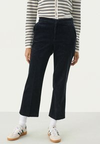Donker marineblauwe corduroy broek met een rechte pijp, voorzien van zijzakken en een hoge tailleband, gecombineerd met witte sokken en sneakers.
