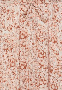 Light pink fabric with reddish-brown abstract floral pattern and a tied drawstring at the waist.