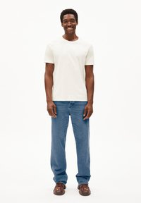 Witte korte mouwen t-shirt gecombineerd met lichtblauwe rechtliggende jeans en bruine, gestructureerde schoeisel. Eenvoudig ontwerp, casual pasvorm, minimale details.