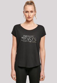 Svart t-skjorte med kort erme og rund hals. Har et sølvfarget "Fantastic Beasts" grafikk på forsiden. Lett stoff, avslappet passform.