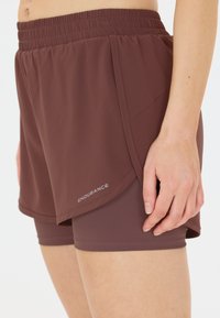 Braune Sportshorts mit elastischem Bund, geschichtetem Design und kontrastierender innerer Schicht. Mit "ENDURANCE"-Logo in Weiß.