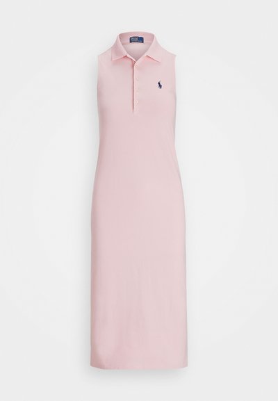 Polo-mekko vaaleanpunaisena, jossa on kaulus, hihaton muotoilu, viiden napin lista ja tummansininen brodeerattu logo rinnassa.