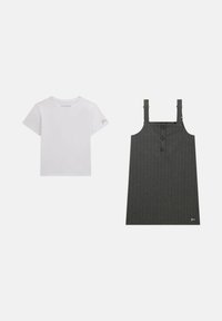 T-shirt bianco a maniche corte con logo sulla manica accanto a un abito grigio scuro a righe con spalline regolabili e chiusura frontale a bottoni.