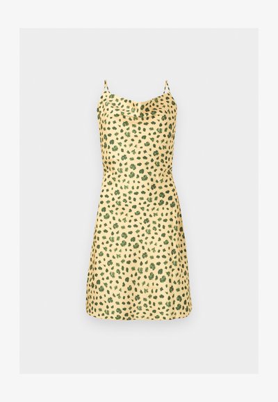 Κίτρινο φόρεμα slip με λεπτές τιράντες και πράσινο φυλλώδες μοτίβο, με ελαφρώς ραμμένη λαιμόκοψη και μήκος πάνω από το γόνατο.