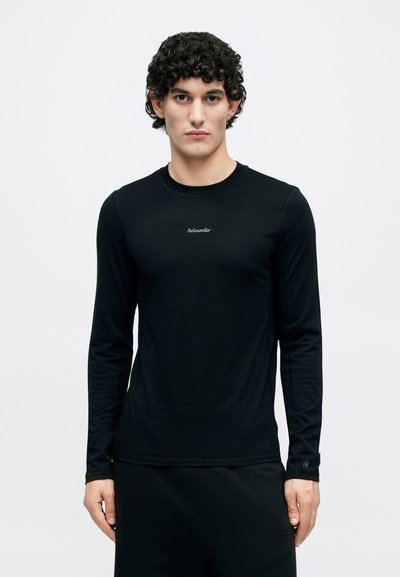 Black long-sleeve shirt made of soft fabric, featuring a round neck and subtle logo detail on the chest, with a fitted design and long sleeves.