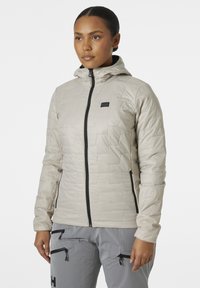 Lichtbeige geïsoleerde jas met een aansluitend ontwerp, capuchon en zwarte rits. Heeft een gequiltde textuur en een klein logo op de borst.