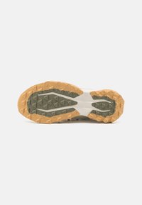 Suela de zapato que presenta un diseño robusto con un patrón de tracción geométrica en marrón y verde, superficie texturizada y una base blanca sólida.