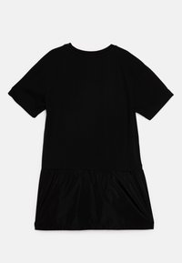 Must mustriga kleit lühikeste varrukatega, T-särgi ülaosa ja voolava, läikiva musta pliseeritud alumise osaga. Lihtne disain ümmarguse kaelusega ja põlvekõrgune pikkus.