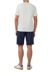 Heren witte katoenen t-shirt, marineblauwe shorts en witte sneakers met marineblauwe accenten. T-shirt heeft een ronde hals en korte mouwen.