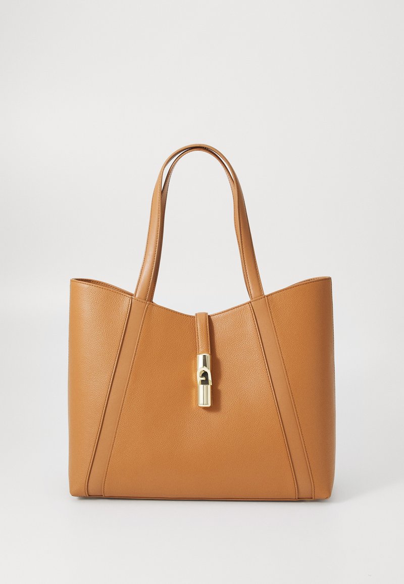 Sac fourre-tout en cuir marron, présentant des lignes épurées, des poignées doubles et un détail de fermoir doré au centre. Texture lisse avec une forme structurée.
