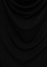 Tissu noir doux avec des plis délicats créant des ombres courbes sur une surface texturée.