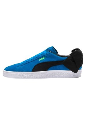 Baskets en daim bleu avec accents noirs, semelle en caoutchouc blanc et un détail unique en boucle noire au talon. Présente un design à lacets et un logo.