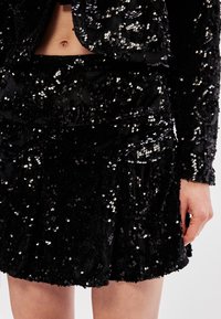 Svart paljettblazer och kjolset med en texturerad yta, med en figurnära design och dekorerad med reflekterande paljetter överallt.