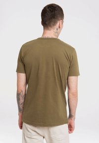 Olivgrünes kurzärmliges T-Shirt aus Baumwolle, runder Halsausschnitt, glatte Textur, mit sichtbaren Nähten und leicht gewelltem Saum.