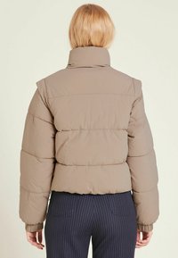 Kaffefarvet dunjakke med høj krave, tekstureret stof og ribbet manchetter. Figursyet design, kort længde og glat finish.