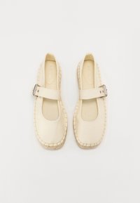 Zapatos Mary Jane beige hechos de cuero suave, con puntera redonda, hebilla metálica ajustable y suela de yute trenzado con costuras.