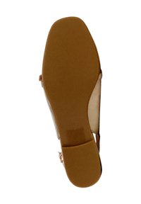 Suola in gomma color tan di una scarpa con un motivo testurizzato, caratterizzata da una parte superiore di colore chiaro e un sottile cinturino alla caviglia.