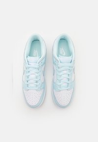 Nike sneakers med en ljusblå läderövre, vit perforerad tå och kontrasterande vita snörning. Diskret logotyp på tungan.