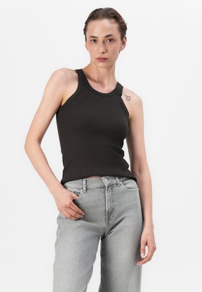 Top negru din bumbac cu model în relief, cu decolteu rotund și brațe largi, asortat cu blugi gri deschis, cu talie înaltă și croială dreaptă. Textură de țesătură netedă.