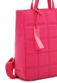 Bolso de mano rosa con un diseño acolchado, hecho de material suave. Cuenta con asas dobles y una correa tejida desmontable. Etiqueta adjunta.