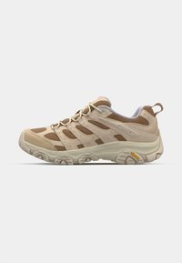 Beige tursko med mesh- og semsket skinn, gummisåle og snøringssystem. Har teksturerte paneler og Vibram-merke på siden.