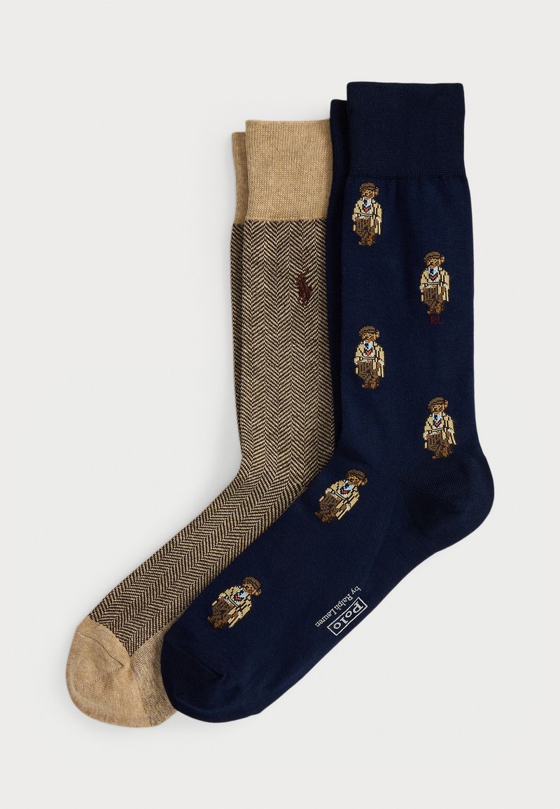 Dos pares de calcetines doblados: uno beige con un patrón de espiga y un pequeño logo de caballo, y otro azul marino con pequeñas ilustraciones de golfistas vintage.