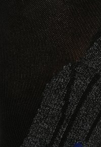 Svart stickad tyg med en texturerad yta, som har ett grått och blått randigt mönster. Ytan är något upphöjd och mjuk.