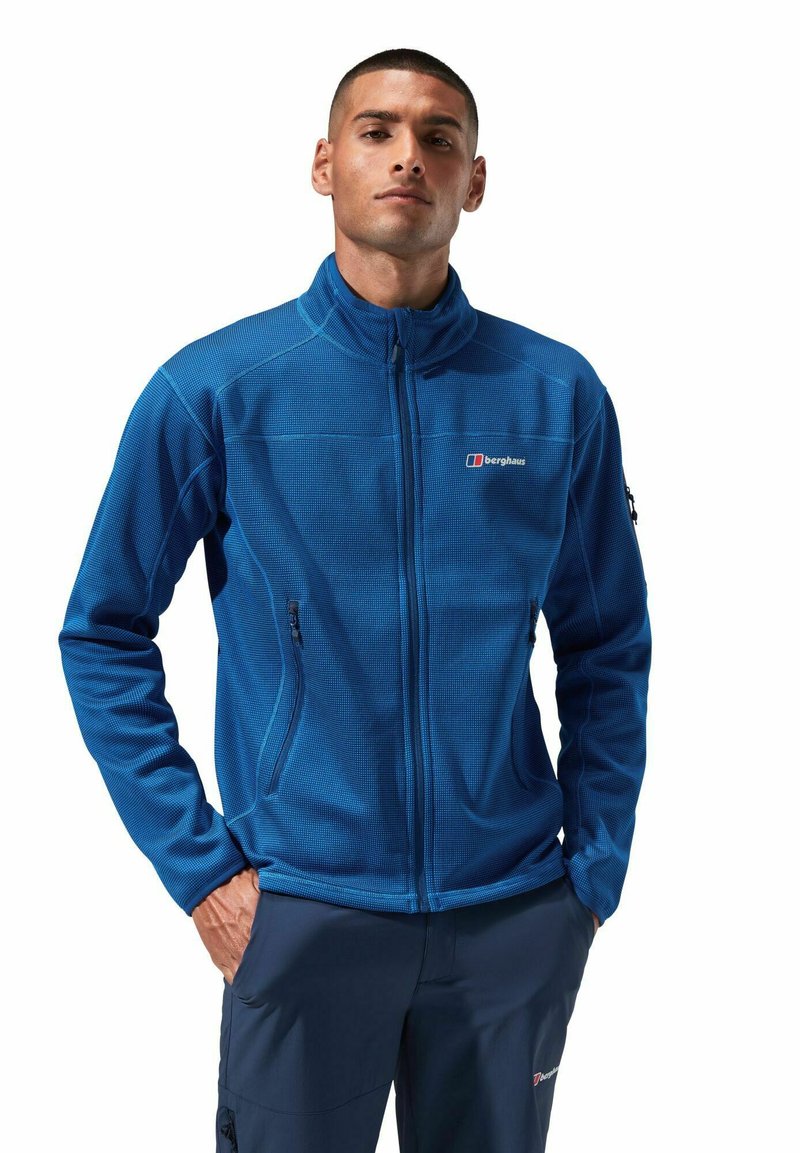 Blaues Reißverschluss-Fleecejacke mit strukturiertem Stoff, zwei seitlichen Taschen und einem Logo auf der linken Brust. Sie hat einen hohen Kragen und eng anliegende Ärmel.