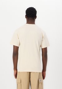 Light beige cotton t-shirt with short sleeves, a crew neckline, and a relaxed fit. Plain design with no visible patterns or accents.