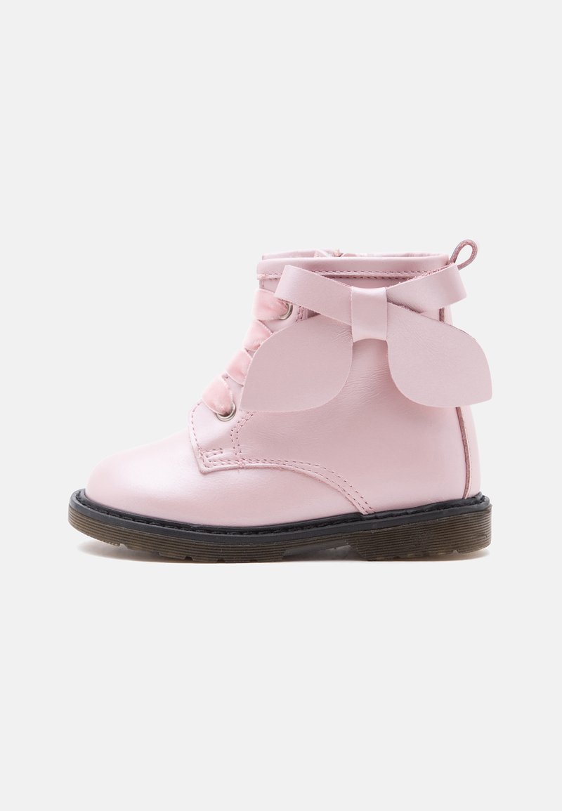 Bottine enfant rose avec semelle noire, lacets à l'avant et grand nœud décoratif sur le côté.