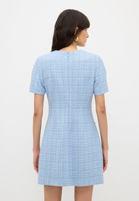 Světle modré šaty s krátkým rukávem vyrobené z texturované látky, s pevnou siluetou a zapínáním na zip na zadní straně. Jednoduchý design bez vzorů.
